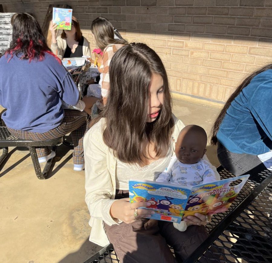 Angelica Cruz-Salgado (10) reads to her baby on a trip to the schools outdoor classroom with the Child Development class.
