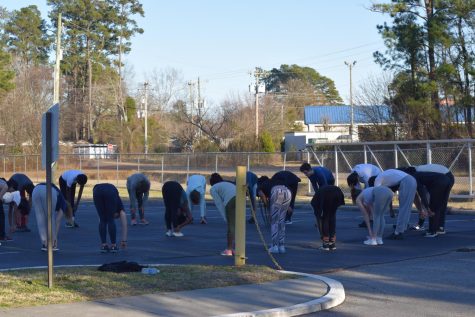 Members of the track team warm up in the parking lot because the track and football field are under construction this season.