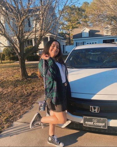 Bree Smith smiles next to her Honda Civic, which she says thankfully gets good gas mileage during this time of surging gas prices.