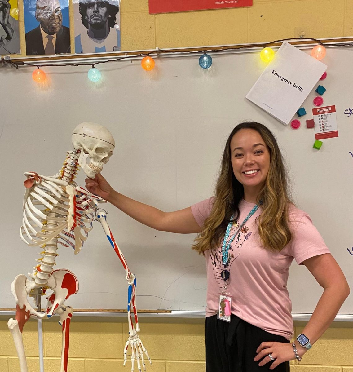Health Sciences teacher Ms. Noel Griffin poses with a skeleton in her classroom.