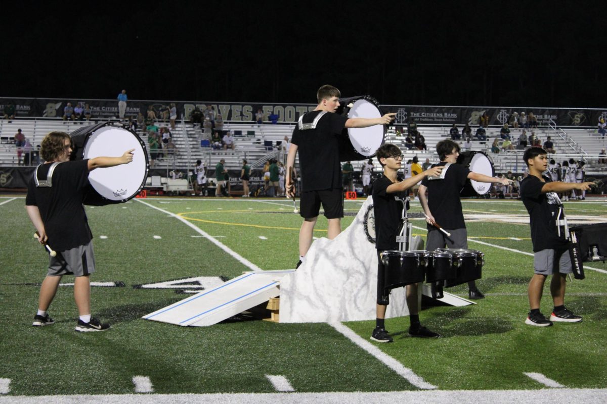 Band members perform a number from their competition piece at a football game.