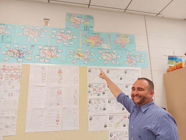 Mr. Robert Morales points to his class map projects.