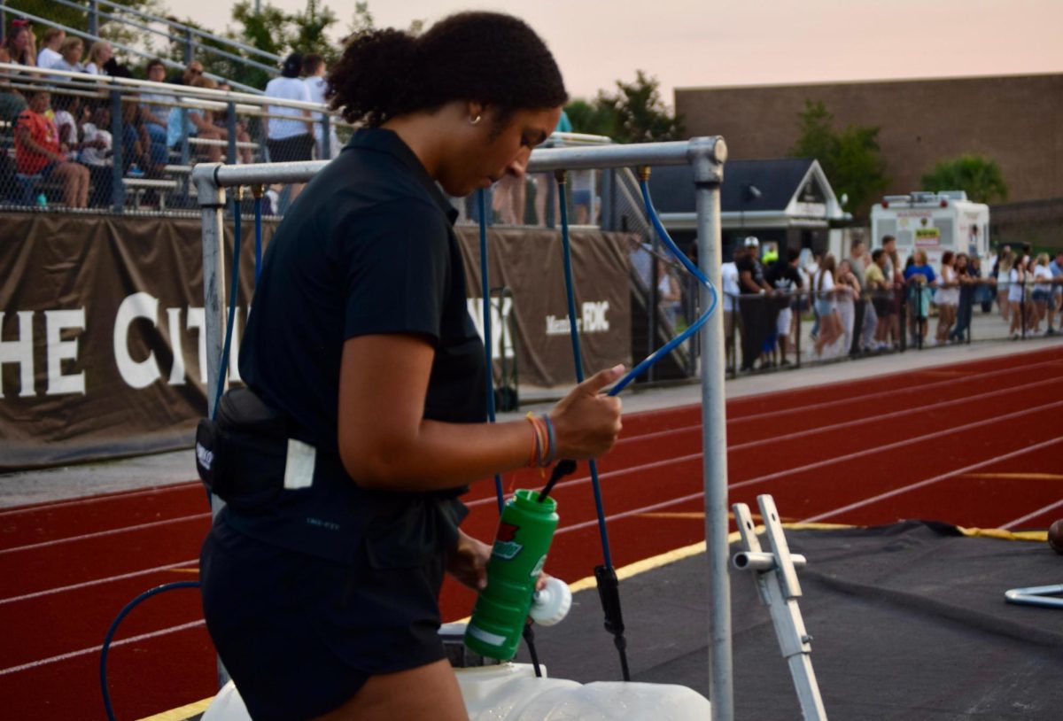 Senior Pebbles Chestnut works as an athletic trainer at a football game.