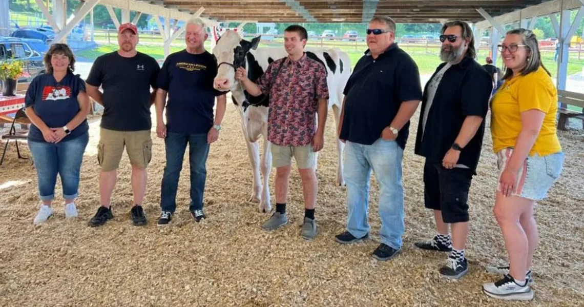 Participants at the Lewis County Fair gather with a Holstein cow for a fundraiser supporting ALICE families